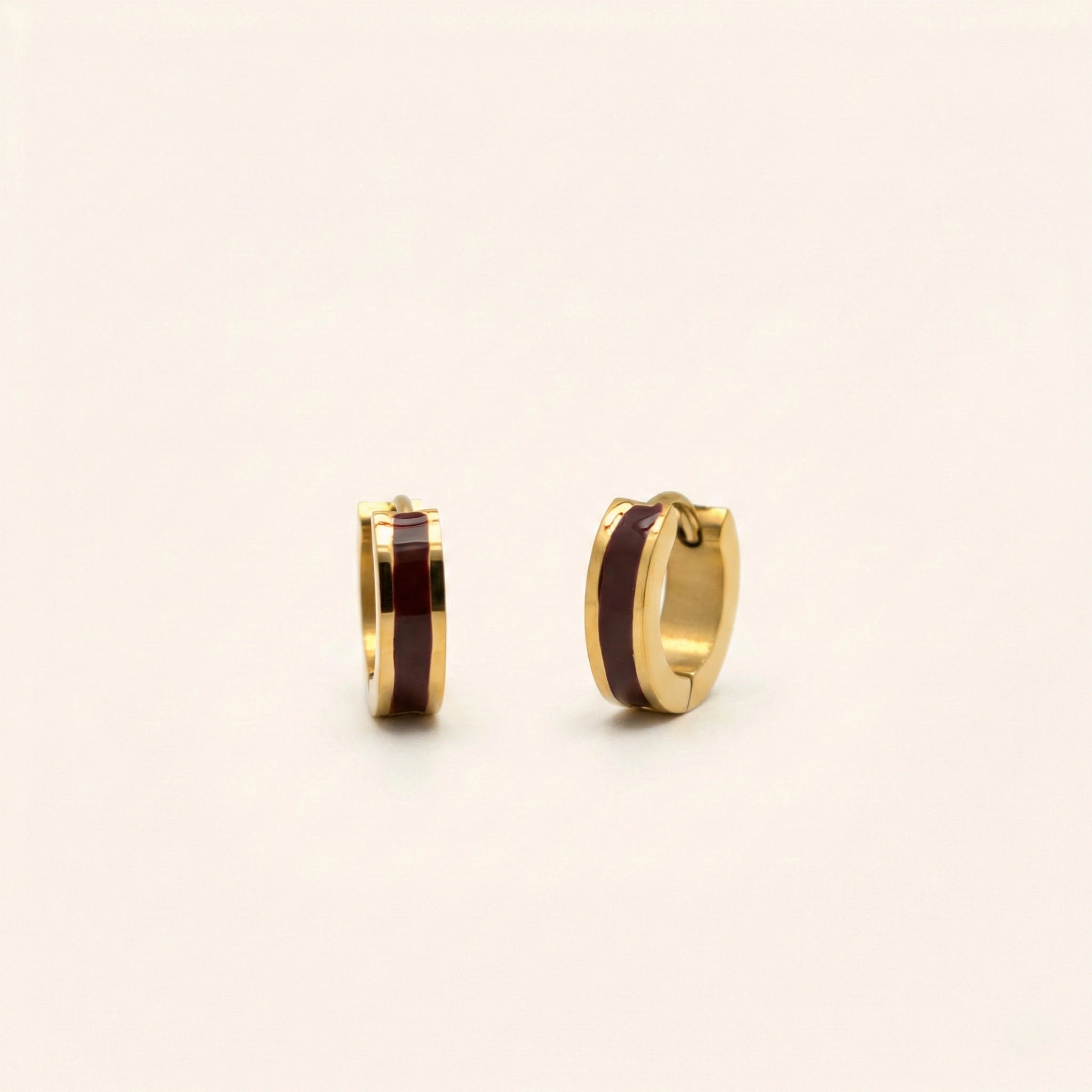 Gold hoop earrings with brown center on a light beige background